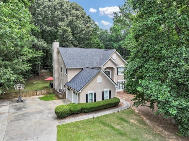 view of front of property with a shingled roof, a chimney, fence, stucco siding, and driveway