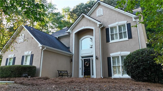 traditional home featuring stucco siding and a shingled roof