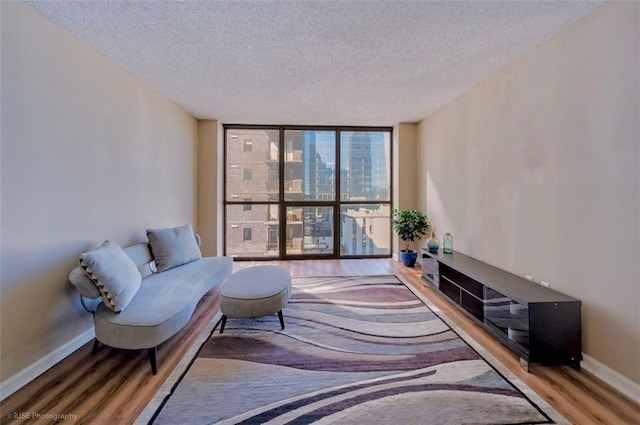 sitting room with a textured ceiling, floor to ceiling windows, wood finished floors, and baseboards