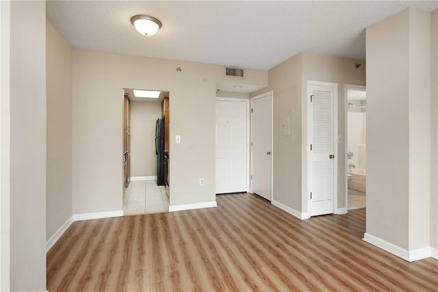 unfurnished room featuring visible vents, light wood-style flooring, and baseboards