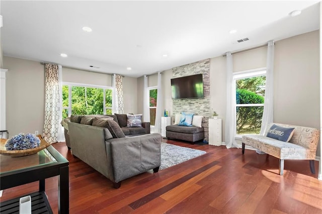 living area with visible vents, a wealth of natural light, and dark wood finished floors
