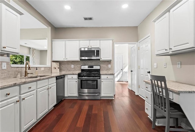 kitchen with visible vents, appliances with stainless steel finishes, a sink, white cabinets, and dark wood-style floors