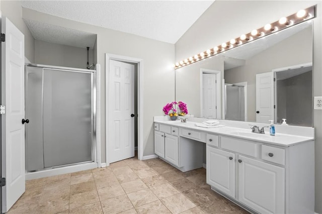 bathroom with double vanity, vaulted ceiling, a sink, and a stall shower