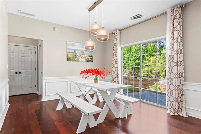 dining room featuring a decorative wall, visible vents, a wainscoted wall, and hardwood / wood-style floors