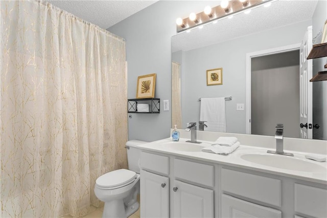 bathroom with a sink, double vanity, toilet, and a textured ceiling