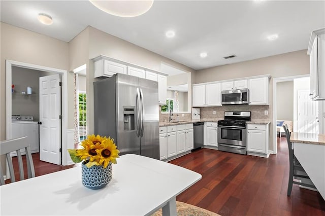 kitchen featuring washer / clothes dryer, decorative backsplash, appliances with stainless steel finishes, and white cabinets
