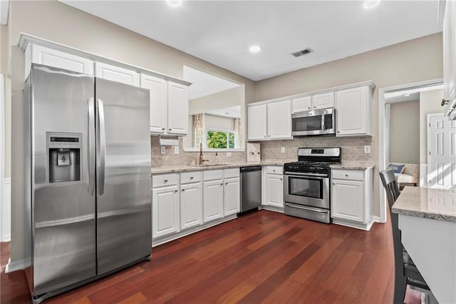 kitchen featuring visible vents, dark wood-style flooring, white cabinetry, a sink, and stainless steel appliances