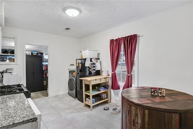 interior space with washer / clothes dryer, a textured ceiling, and light tile patterned floors