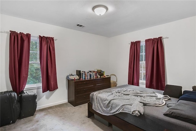 bedroom featuring light colored carpet and multiple windows