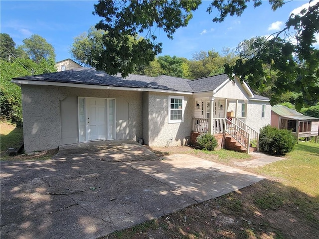 single story home featuring a porch, a front yard, and a garage