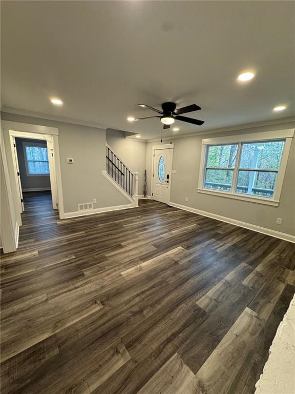 unfurnished living room featuring dark hardwood / wood-style floors, ceiling fan, and crown molding