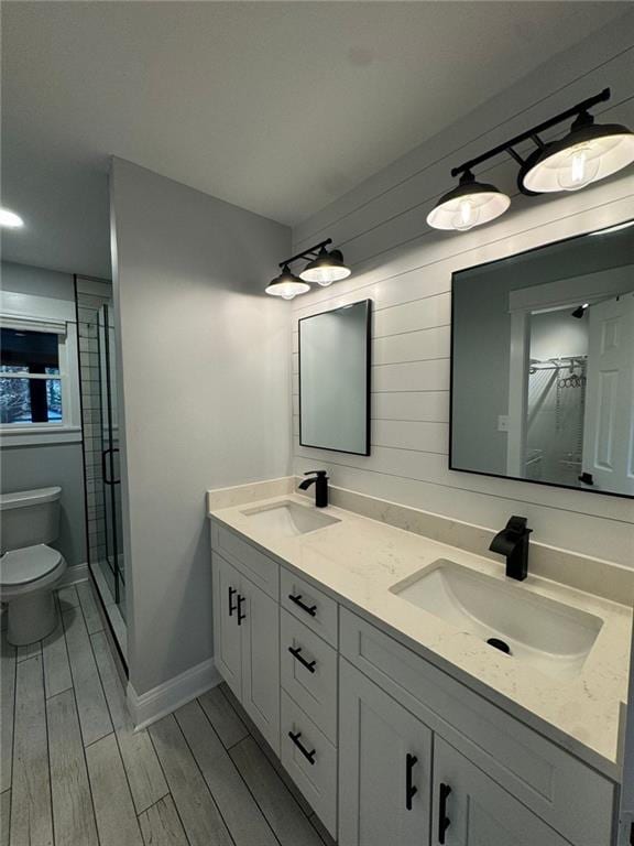 bathroom with an enclosed shower, vanity, toilet, and wood-type flooring