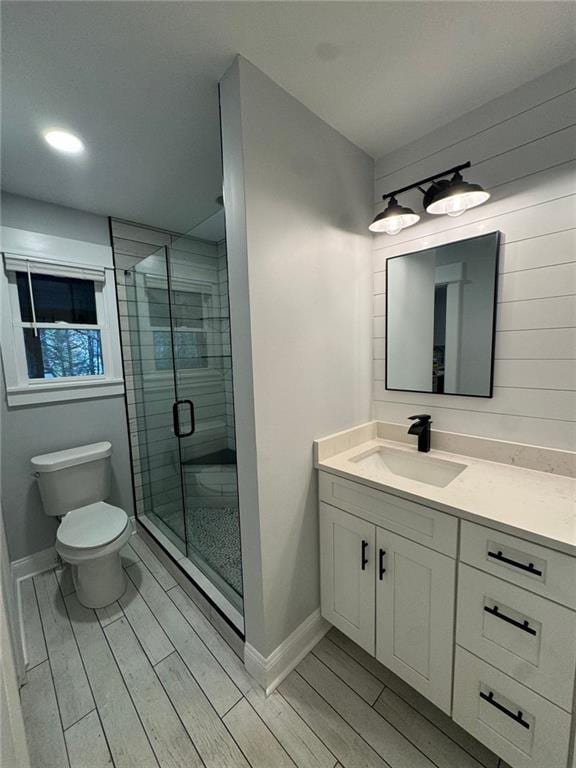 bathroom featuring vanity, toilet, and a shower with door