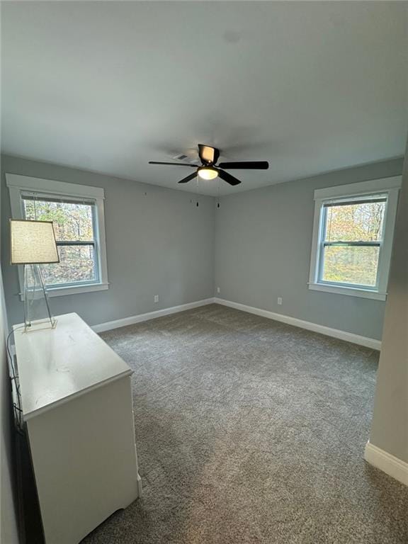 carpeted empty room featuring a wealth of natural light and ceiling fan