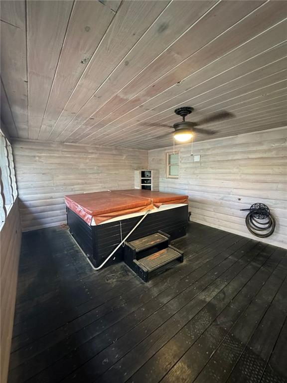 interior space with dark hardwood / wood-style flooring, wooden ceiling, and wooden walls