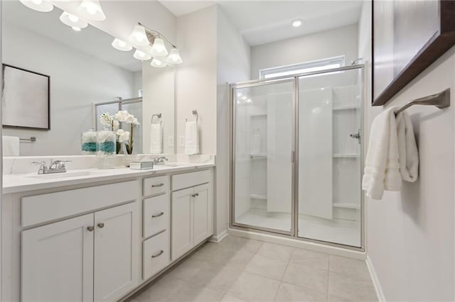 full bathroom with double vanity, tile patterned flooring, a shower stall, and a sink