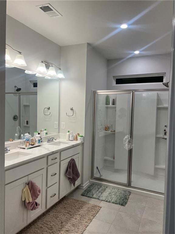 full bathroom with visible vents, a sink, a shower stall, and double vanity