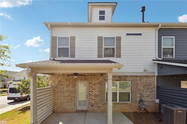 rear view of property with ceiling fan, cooling unit, and brick siding