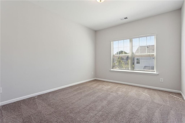 carpeted spare room featuring visible vents and baseboards