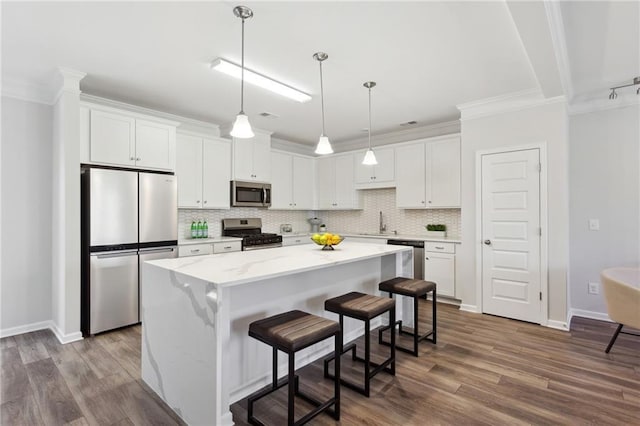 kitchen with decorative backsplash, appliances with stainless steel finishes, a center island, white cabinetry, and a sink