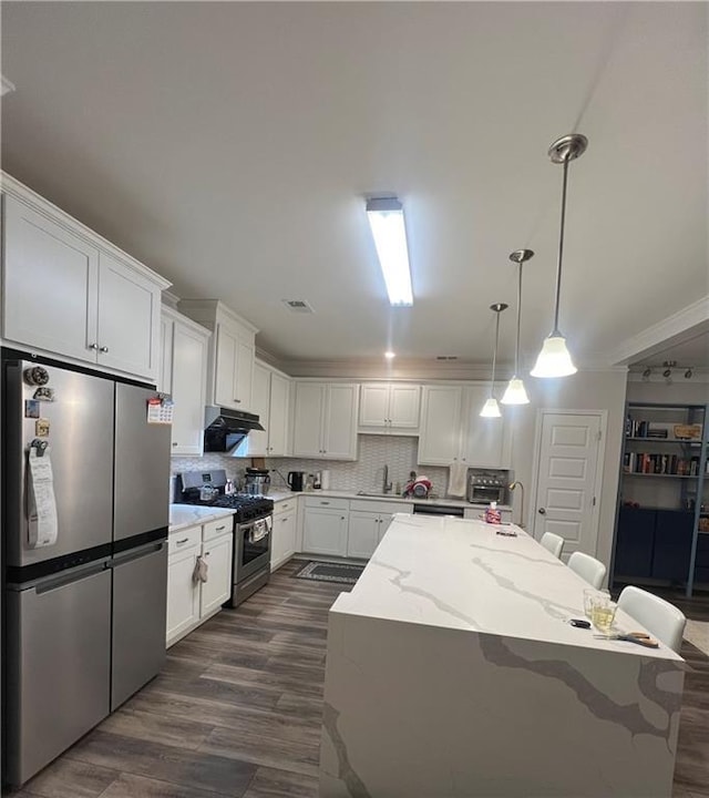 kitchen featuring white cabinets, a kitchen island, stainless steel appliances, and exhaust hood