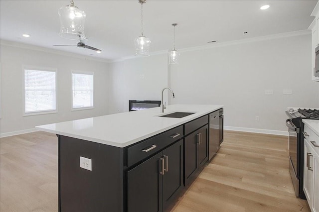 kitchen with sink, light hardwood / wood-style flooring, an island with sink, white cabinets, and appliances with stainless steel finishes