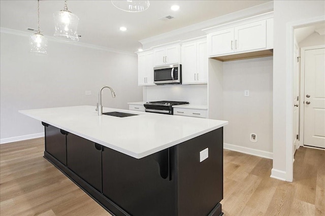 kitchen with a kitchen island with sink, white cabinets, sink, light hardwood / wood-style floors, and stainless steel appliances