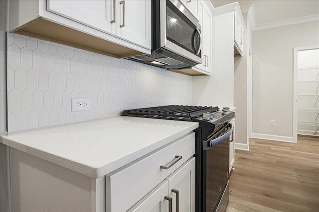 kitchen featuring backsplash, white cabinetry, light wood-type flooring, and appliances with stainless steel finishes