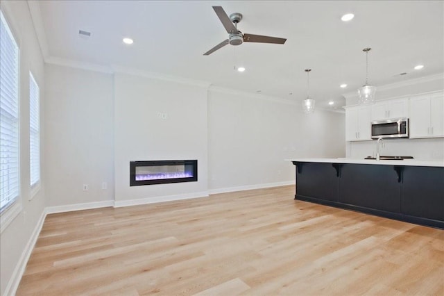 kitchen featuring a breakfast bar area, ornamental molding, light countertops, a glass covered fireplace, and stainless steel microwave