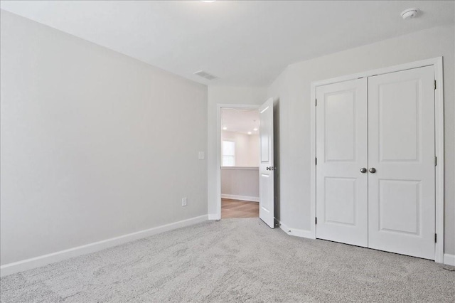 unfurnished bedroom with light colored carpet and a closet