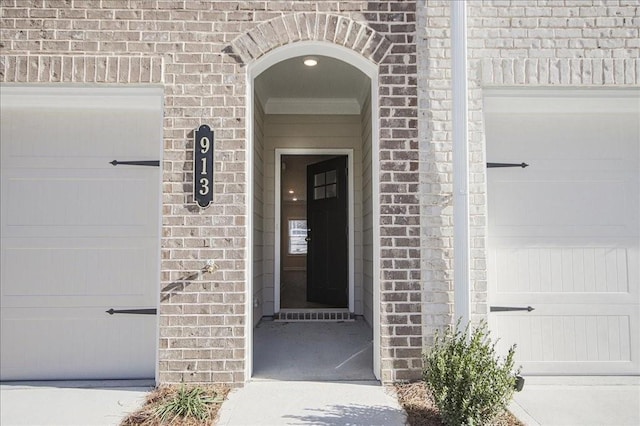 doorway to property featuring brick siding and an attached garage