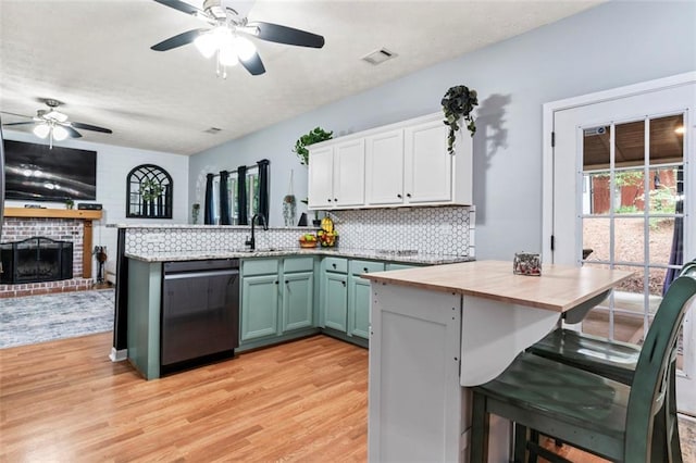 kitchen with ceiling fan, a brick fireplace, white cabinetry, dishwasher, and light wood-type flooring