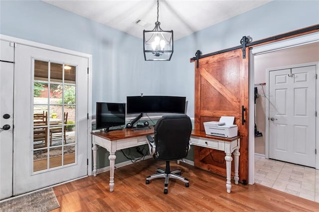 office with light hardwood / wood-style flooring and a barn door