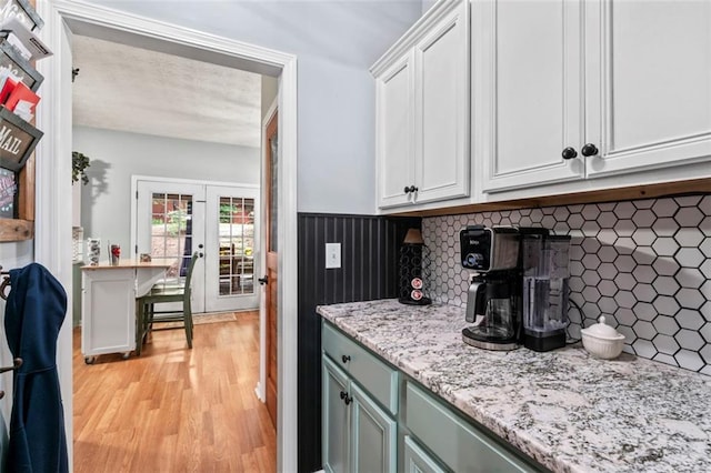 kitchen featuring decorative backsplash, white cabinets, light wood-type flooring, a textured ceiling, and french doors