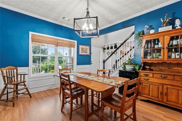 dining area with light hardwood / wood-style floors, crown molding, and a chandelier