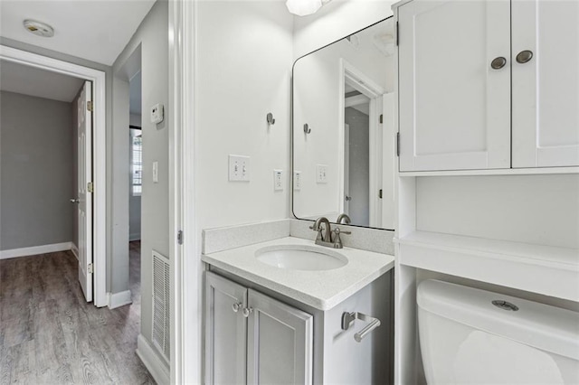 bathroom with hardwood / wood-style floors, vanity, and toilet