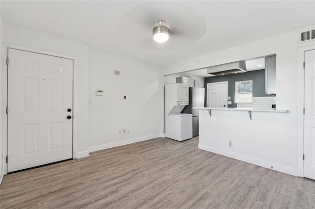 interior space with stacked washer / drying machine and light hardwood / wood-style flooring