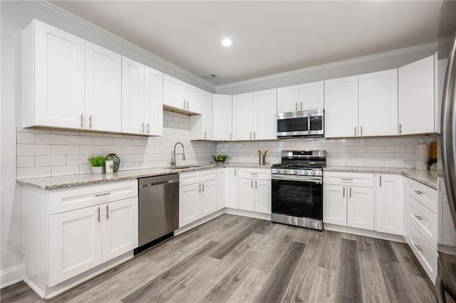 kitchen featuring a sink, stainless steel appliances, wood finished floors, and white cabinetry