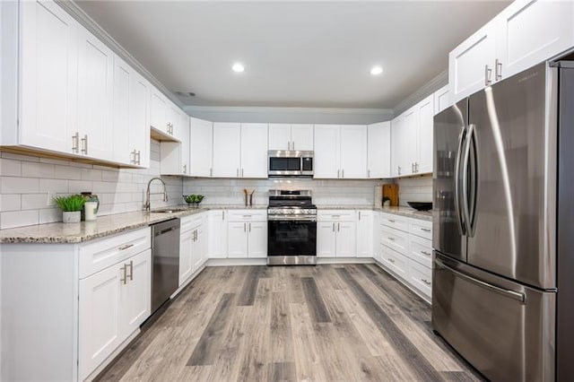 kitchen featuring a sink, light stone counters, tasteful backsplash, wood finished floors, and stainless steel appliances