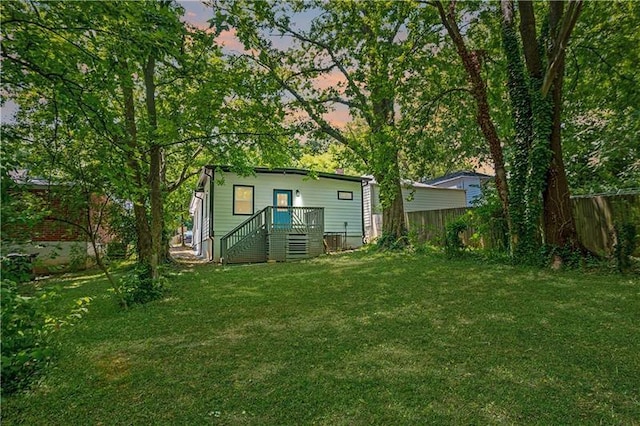 back of house at dusk with a yard and fence