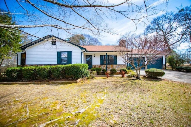 single story home with driveway, stone siding, a chimney, and an attached garage