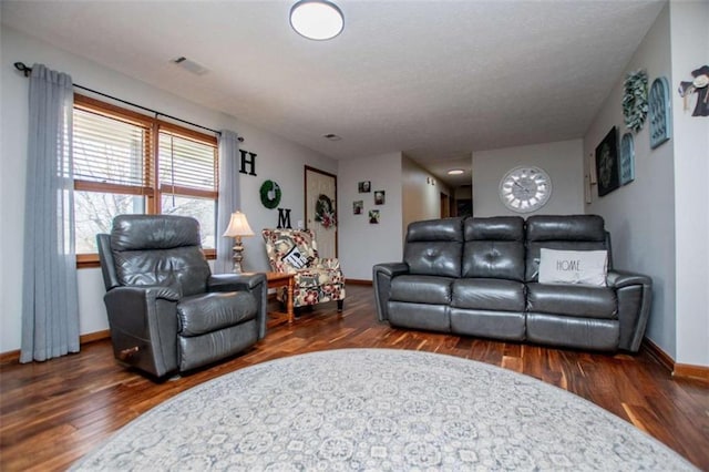 living area with visible vents, baseboards, and wood finished floors