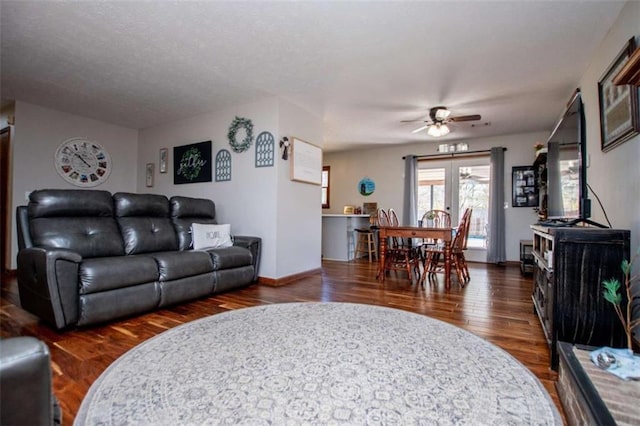 living area with ceiling fan, a textured ceiling, wood finished floors, baseboards, and french doors