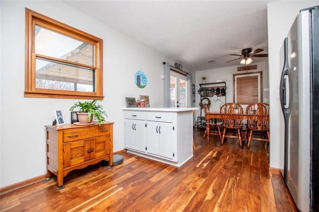 kitchen with white cabinets, dark wood finished floors, freestanding refrigerator, a peninsula, and light countertops