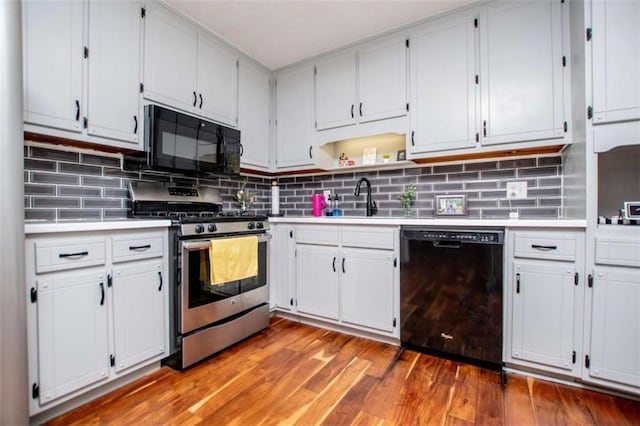 kitchen featuring a sink, black appliances, light countertops, and light wood-style floors