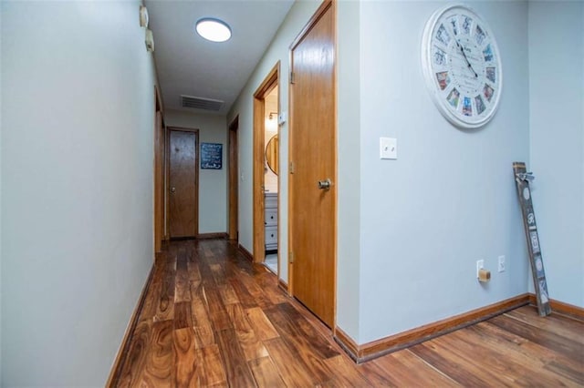 hallway with visible vents, baseboards, and wood finished floors