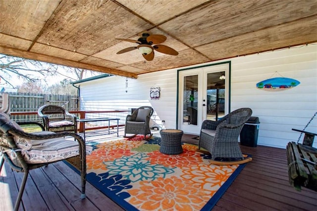 wooden terrace featuring fence, a ceiling fan, and french doors