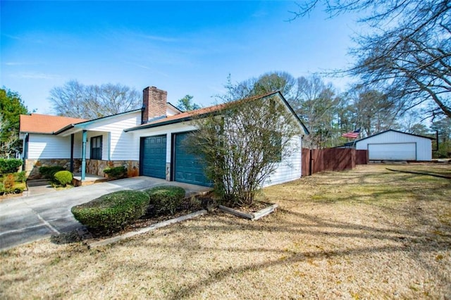 view of home's exterior featuring a garage, a lawn, stone siding, a chimney, and fence