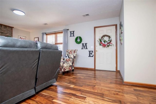 living area with wood finished floors, visible vents, and baseboards