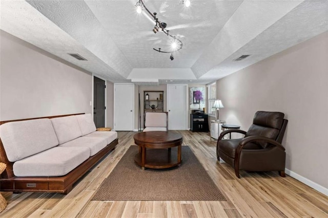 610 Lake Dr, Snellville, GA 30039 - living area featuring a tray ceiling, light wood-type flooring, baseboards, and a textured ceiling